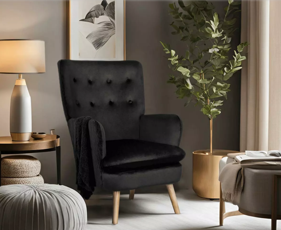 Elegáns fekete fotel, a nappali éke asztali lámpával és zsámollyal